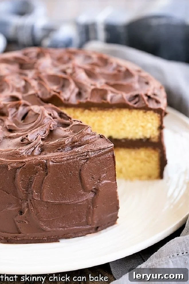 Irresistible Golden Yellow Cake and Decadent Chocolate Buttercream 2 Perfect Yellow Cake Recipe with Chocolate Buttercream on a white cake plate with a slice expertly removed, showcasing its moist interior and rich frosting.