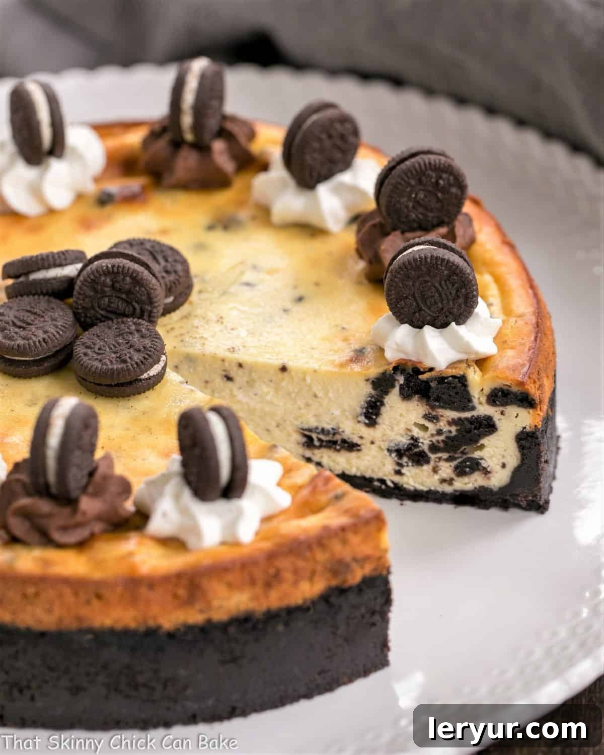 An Oreo Cheesecake with an Oreo cookie crust, served on a white platter, with a single slice removed, inviting guests to enjoy its creamy interior.