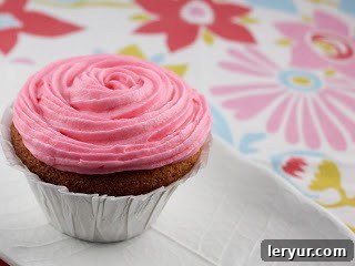 A perfectly frosted vanilla cupcake with a delicate star-tip swirl of pink buttercream