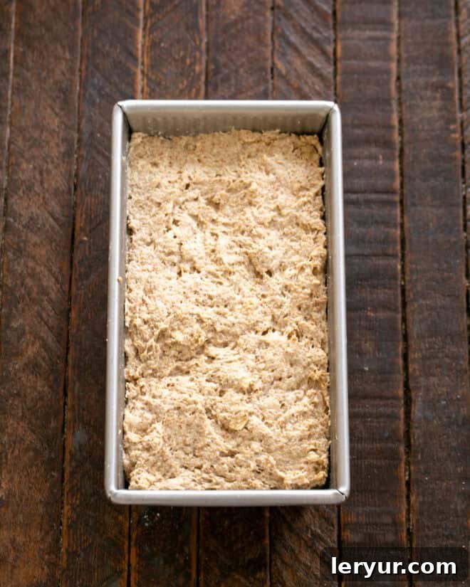Effortless Traditional Irish Soda Bread 6 Dough for Irish Brown Bread being scraped into a prepared loaf pan before baking.