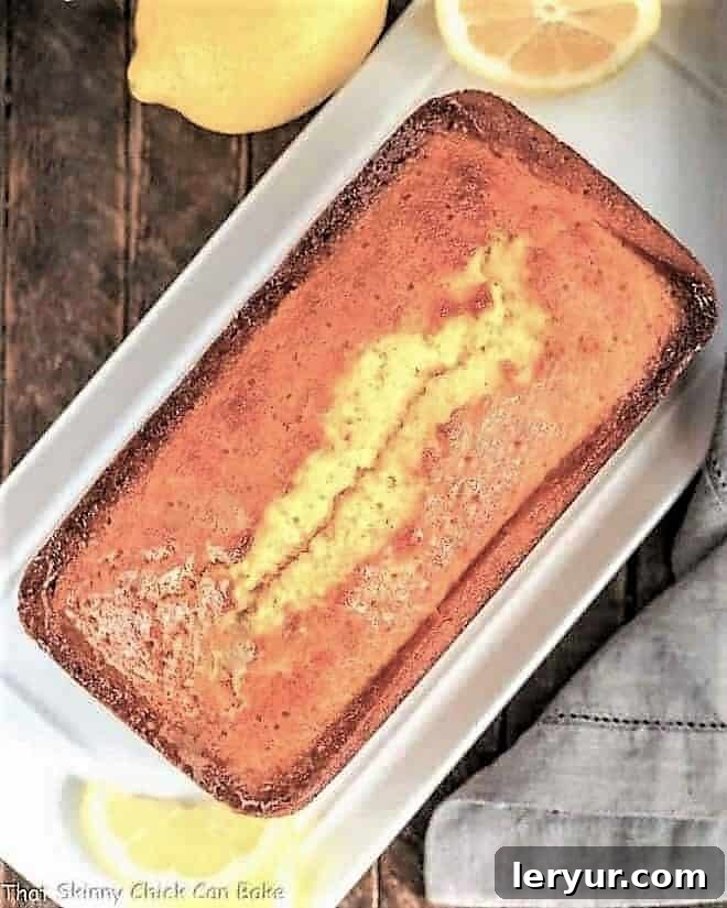 Glazed Lemon Pound Cake - served with whipped cream and berries for a delightful dessert Glazed Lemon Cake Recipe overhead loaf view on a white tray. A perfectly baked lemon pound cake.