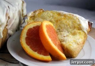 Citrus Burst Pull-Apart Coffee Cake 2 A slice of Orange Pull-Apart Coffee Cake on a white plate, garnished with fresh orange slices, highlighting its tender, layered texture.