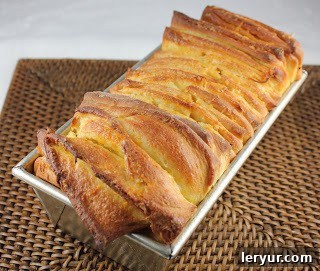 Orange Pull-Apart Coffee Cake - a unique, delicious bread recipe flavored with orange! A close-up view of Orange Pull-Apart Coffee Cake cooling in a loaf pan, emphasizing its fluffy texture and golden crust.