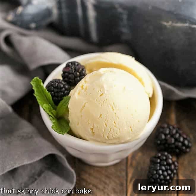 White Chocolate Ice Cream scoops in a white ceramic bowl with berries and mint