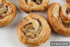 Prosciutto Gruyère Pinwheels made with homemade puff pastry Freshly baked Prosciutto Gruyère Pinwheels, golden and flaky, arranged on a baking sheet, steam gently rising.