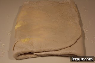Process of making puff pastry pinwheels The puff pastry folded after its first turn, a crucial step in developing its signature layers.