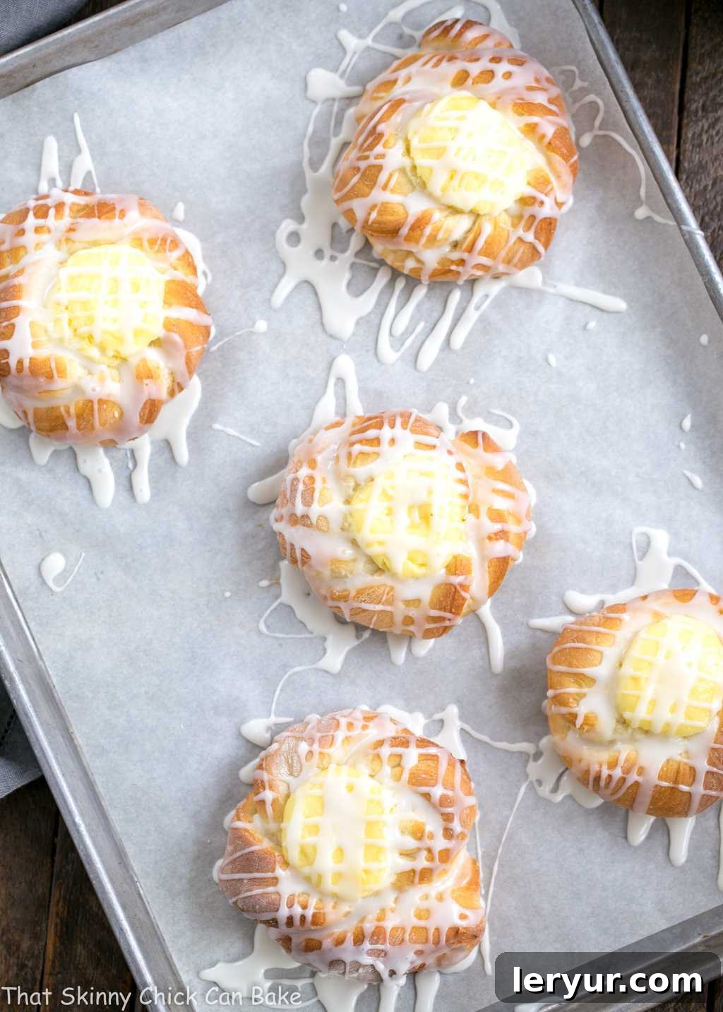 A batch of unbaked Danish Twists with Cream Cheese Filling, perfectly proofed and ready for the oven, laid out on a parchment-lined sheet pan.