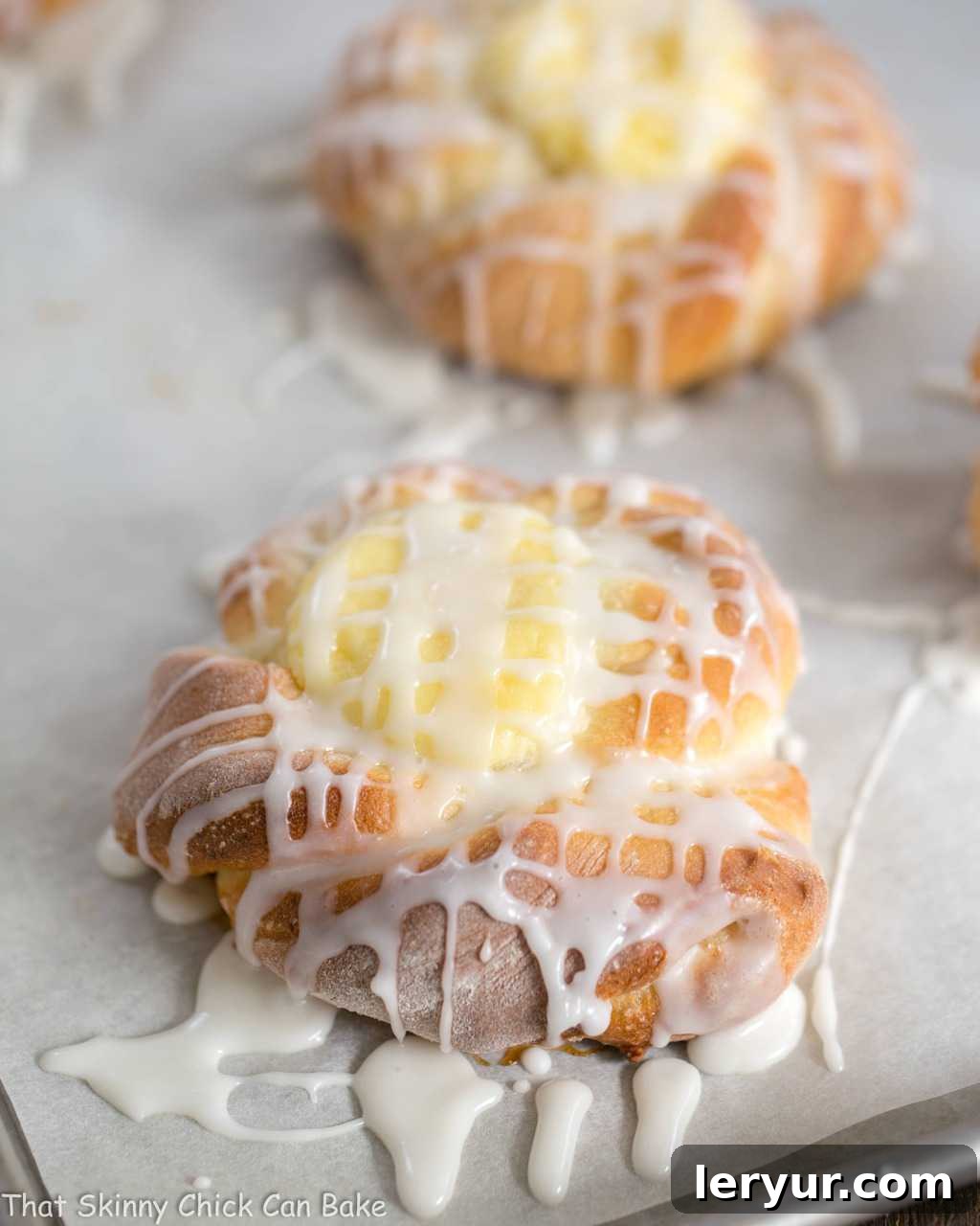 Freshly baked Danish Twists with Cream Cheese Filling, glistening with glaze, arranged on a parchment-lined sheet pan, still warm from the oven.