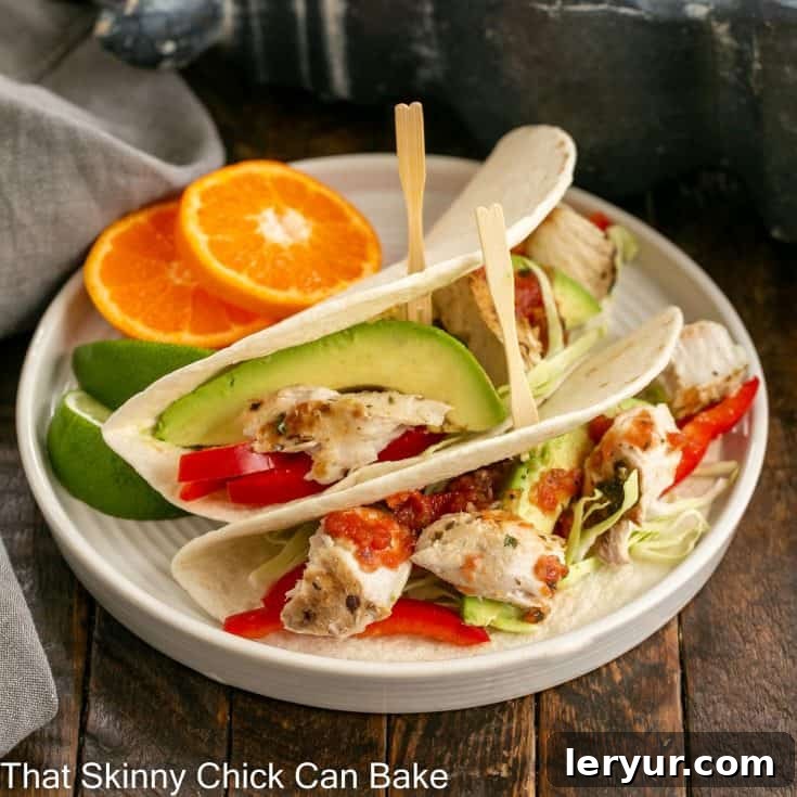 Two grilled fish tacos with vibrant slaw, fresh lime, and a creamy white sauce, beautifully presented on a pristine white plate. This image captures the essence of a delicious and healthy meal.