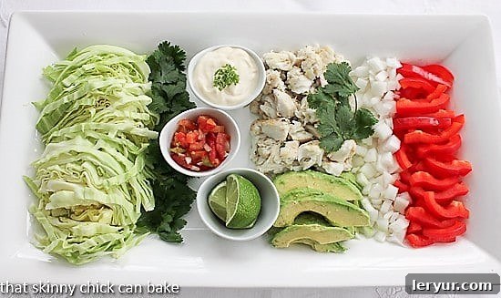 A grand, beautifully arranged platter showcasing an abundant array of grilled fish tacos and all their fresh, colorful fixings, including vibrant shredded cabbage, various salsas, and bright lime wedges. This inviting spread encourages guests to create their own perfect taco combination.
