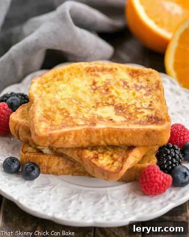 Perfectly cooked Grand Marnier French Toast - an indulgent breakfast choice A stack of golden Grand Marnier French Toast on a white, decorative plate, ready to be served.