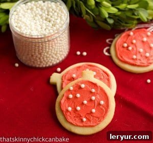 Beautifully frosted cream cheese sugar cookies adorned with festive sprinkles on a red napkin.