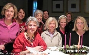 A group of smiling friends enjoying a baking class in a home kitchen, full of holiday spirit.