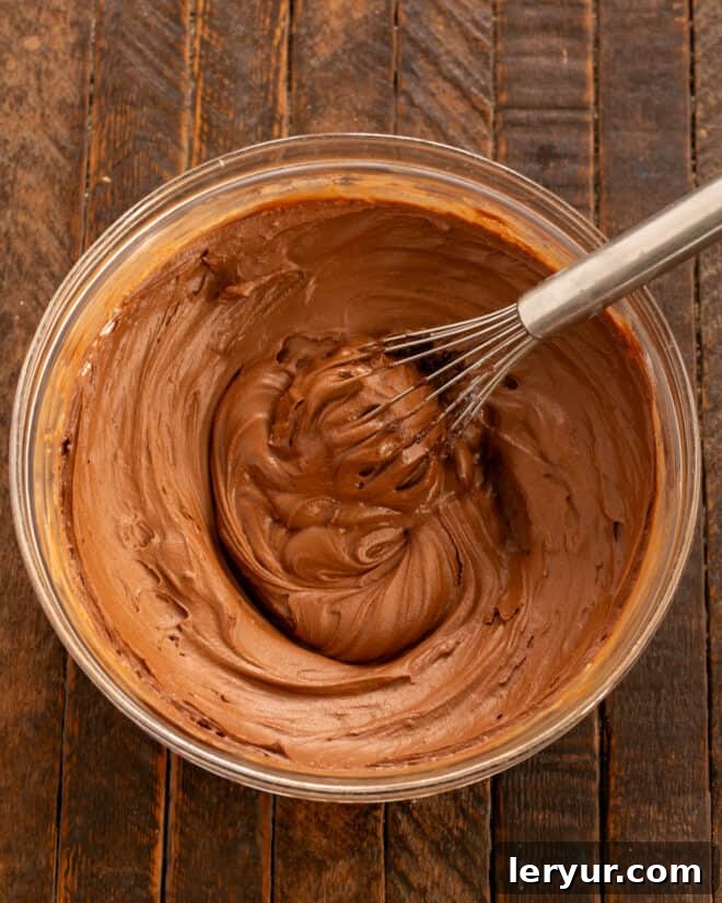 Velvet Night Snack Cakes 13 Vanilla extract being mixed into the prepared chocolate frosting, adding a final touch of flavor to the Black Magic Cake buttercream.