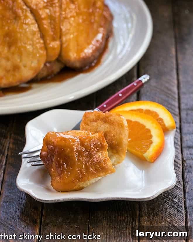 Easy Monkey Bread pieces on a small white plate with orange slices, showcasing a golden-brown, sticky pull-apart bread perfect for breakfast.