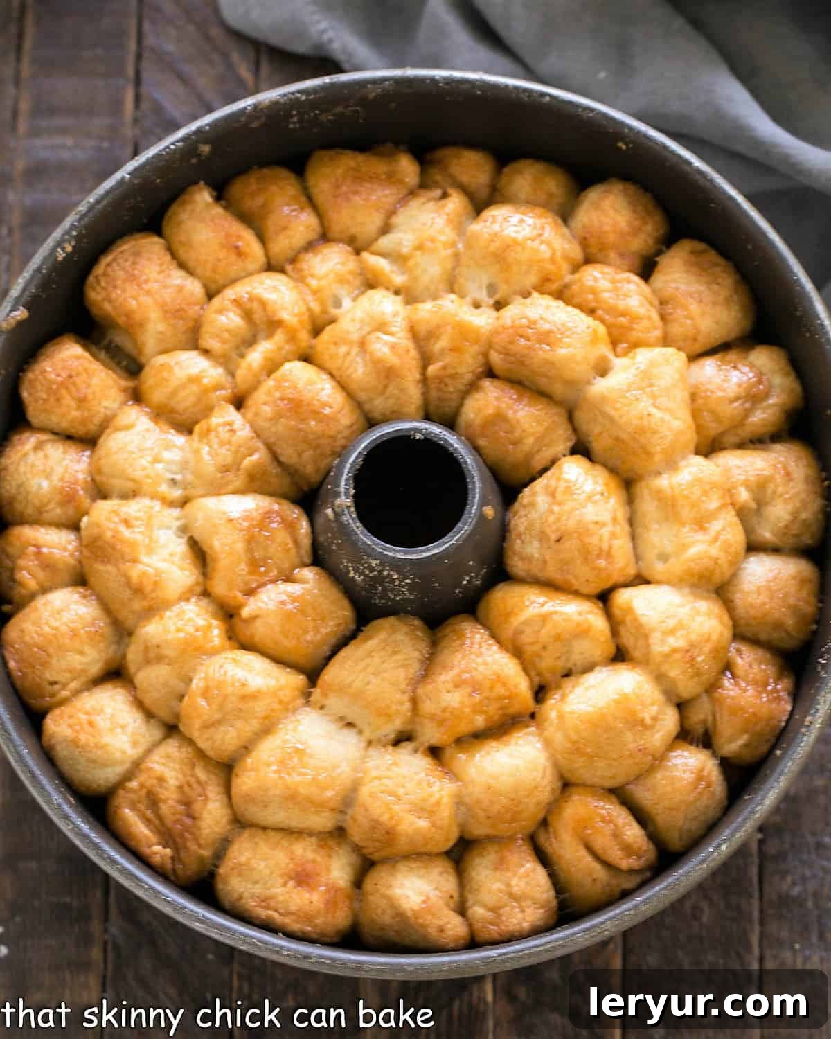 Baked bubble roll in a tube pan before inverting onto a serving dish, showing a perfectly golden-brown crust and bubbling caramel sauce.