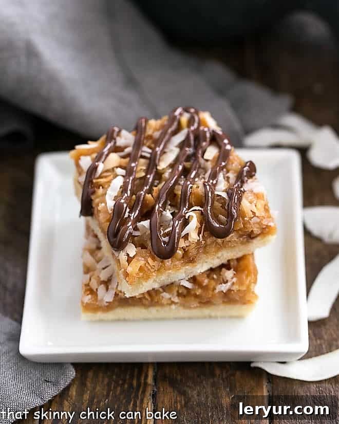 Homemade Samoa Bars - all the same terrific flavors of the classic Girl Scout Cookies with a shortbread base, caramel and coconut topping and chocolate drizzle! Homemade samoa bars stacked on a white plate.