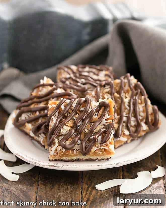 Homemade Samoa Bars - all the same terrific flavors of the classic Girl Scout Cookies with a shortbread base, caramel and coconut topping and chocolate drizzle! Homemade samoa bars on a round plate with shreds of coconut.