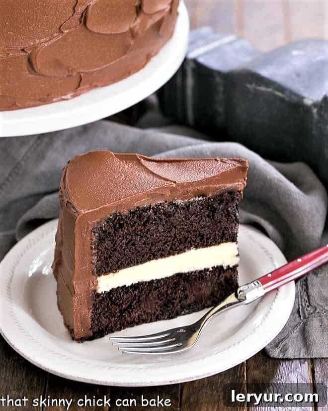 A delectable slice of Chocolate Layer Cake with White Chocolate Ganache on a dessert plate, accompanied by a red-handled fork.