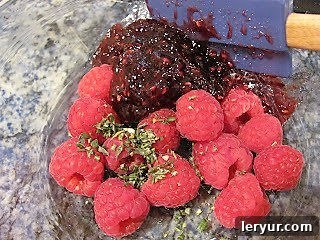 Baked Brie with Raspberries - a spectacular appetizer with creamy brie, a raspberry, rosemary topping and a flaky puff pastry crust! Raspberry Baked Brie Topping ingredients being mixed in a bowl.