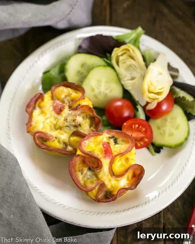 Savory Egg Muffins in Ham Cups - Your Go-To Portable Omelet Overhead view of Egg Muffins in Ham Cups on a small white plate, garnished with fresh herbs.