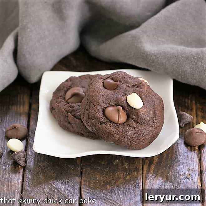 A selection of Quadruple Chocolate Cookies presented on a small, elegant wavy white plate.