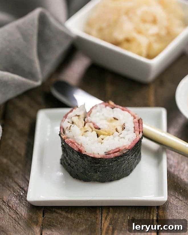 A meticulously prepared Reuben Roll, featuring its distinctive ingredients, presented elegantly on a small white square plate.