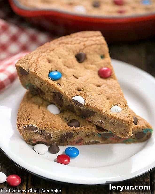 Patriotic Skillet Cookie wedges stacked on a white enamel dessert plate, showcasing the red, white, and blue M&M's.