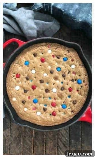 Pressing additional M&M's and chocolate chips onto the warm skillet cookie for garnish.
