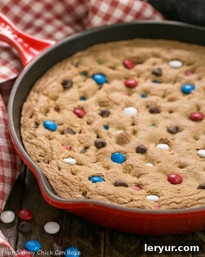Patriotic Skillet Cookie in a red cast iron skillet, garnished with red, white, and blue M&M's.