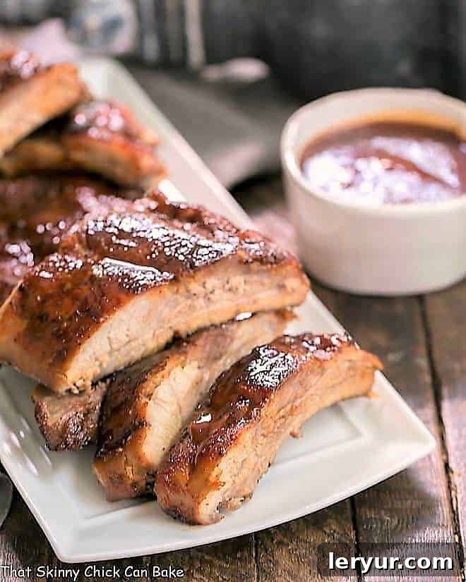 Instant Pot Baby Back Ribs on a white serving tray, garnished with fresh herbs
