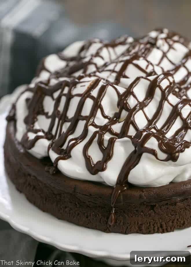 Flourless Chocolate Cake with Marshmallow Frosting on a white cake stand, showcasing its rich texture and fluffy topping.