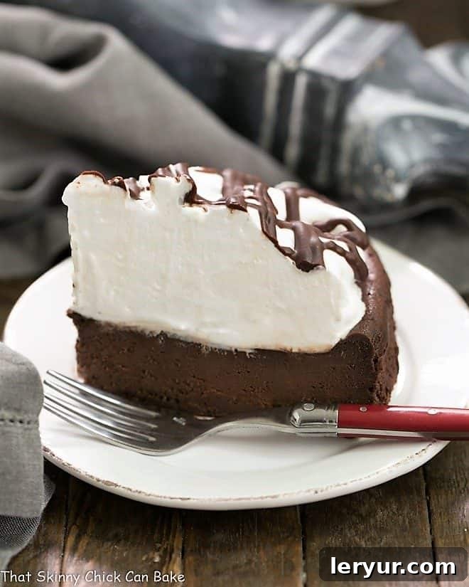 A perfectly portioned slice of Flourless Chocolate Cake with Marshmallow Frosting on a white ceramic plate, ready to be enjoyed.