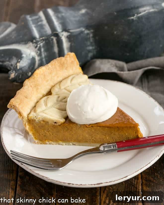 Homemade Pumpkin Pie: The classic recipe made even better with simple tweaks for an easy, adored dessert! A perfectly portioned slice of Homemade Pumpkin Pie resting on a white dessert plate, accompanied by a vibrant red-handled fork.