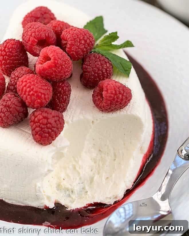 No-Bake cheesecake recipe topped with fresh raspberries with a scoop removed, showcasing its creamy interior.