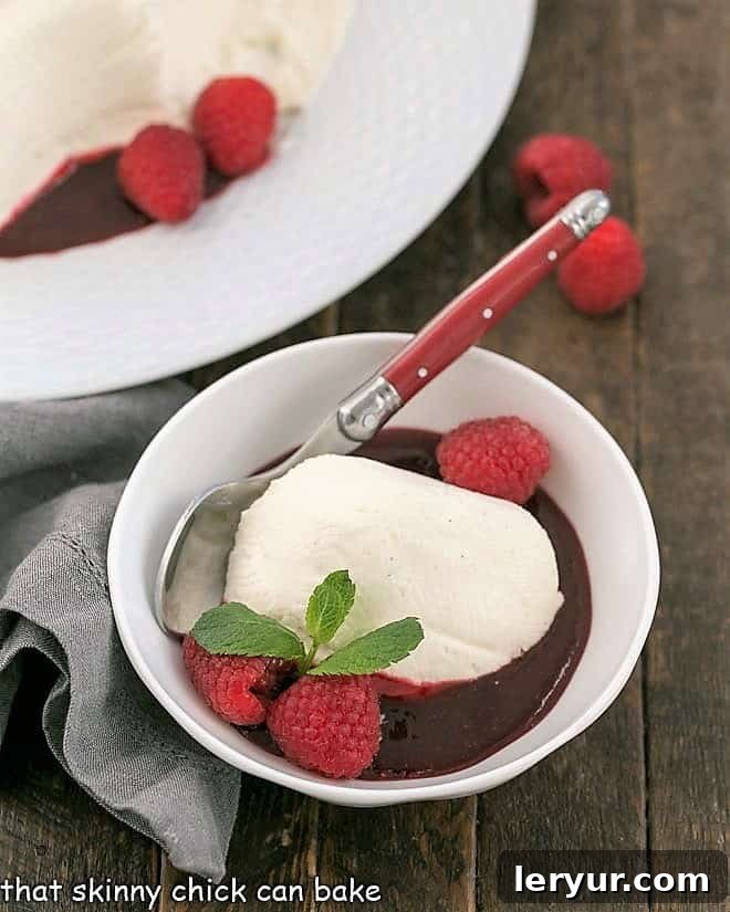 Serving of no bake cheesecake in a bowl with fresh raspberries and mint garnish.