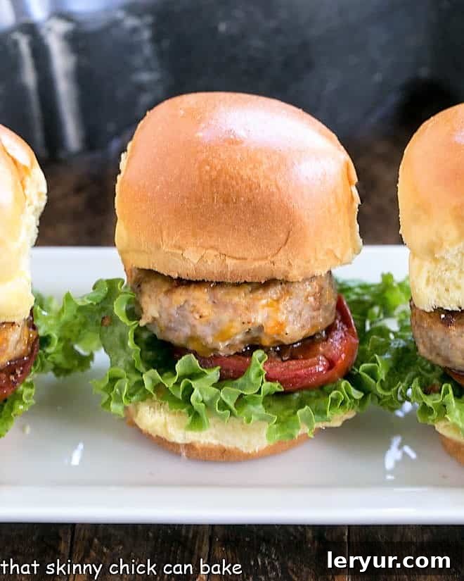 A neat line of Turkey Sliders with Roasted Tomatoes on a white serving tray, showcasing their perfect presentation.