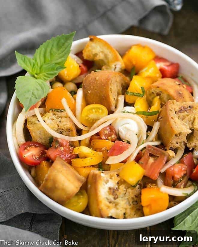 Summer Tomato and Burrata Panzanella Salad - the best of summer in every bite! A stunning Summer Tomato and Burrata Panzanella Salad presented in a white serving bowl, elegantly garnished with fresh basil leaves, ready to be enjoyed on a warm day.