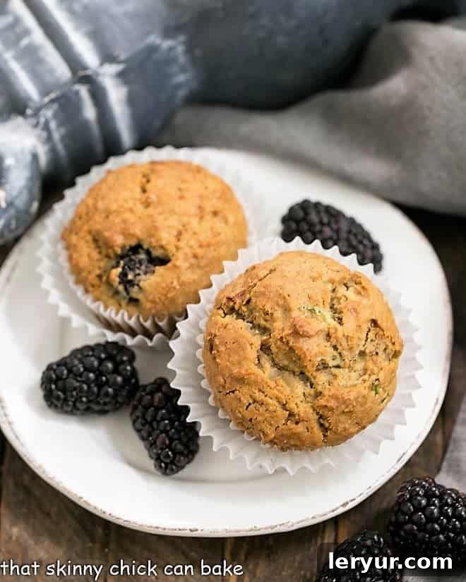 Blackberry Bran Muffins with grated zucchini and full of juicy, plump berries Blackberry Bran Muffins on a white plate garnished with berries
