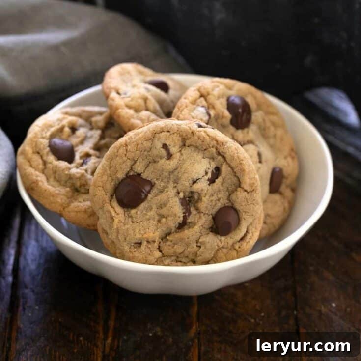 Four killer chocolate chip cookies in a small white bowl.