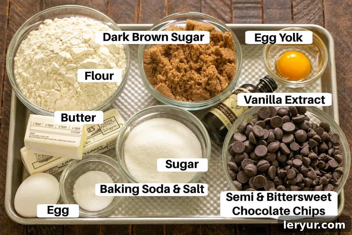 Dangerously Delicious Chocolate Chip Cookies 2 A curated display of high-quality ingredients for killer chocolate chip cookies, including bags of flour, sugars, butter, eggs, and Ghirardelli semisweet and bittersweet chocolate chips, meticulously arranged on a metal sheet pan, ready for baking.