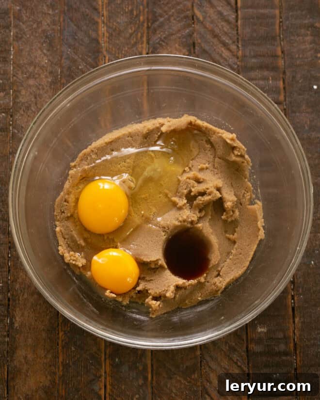 Dangerously Delicious Chocolate Chip Cookies 6 The mixing bowl with creamed butter and sugars, now having a whole egg, an extra egg yolk, and vanilla extract added, ready for the next stage of blending into the cookie dough.