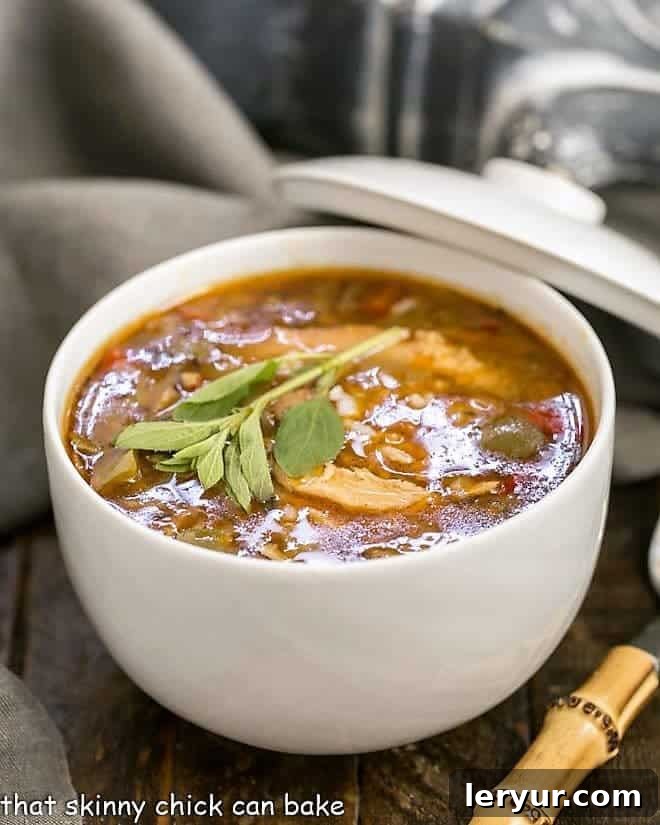 Sausage and Chicken Gumbo - a spicy, flavorful Cajun chicken stew that will warm you to your bones! A bowl of Sausage and Chicken Gumbo with a bamboo spoon