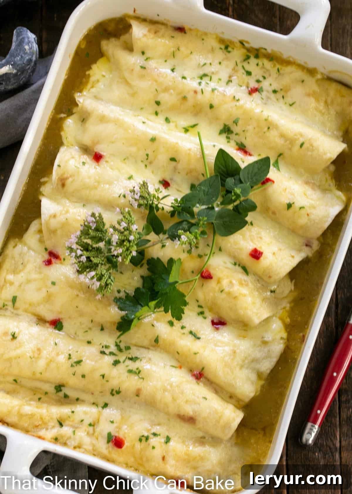 Creamy Chicken Enchiladas - an easy delicious weeknight meal! Overhead view of casserole full of green enchiladas topped with herb sprigs.
