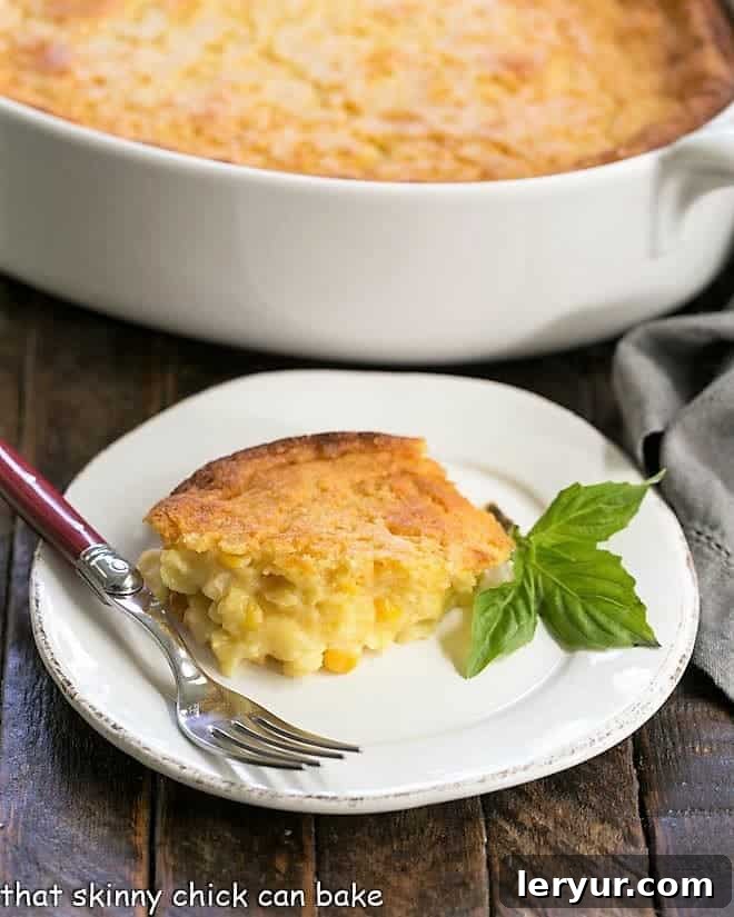Cream Corn Casserole - a creamy, simple, and satisfying corn pudding side dish, ideal for any gathering or family meal! Easy Sweet Corn Casserole on a small white plate garnished with fresh basil leaves.