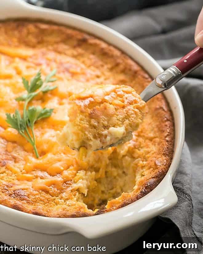 No Fuss Creamy Corn Casserole 2 Spoonful of corn pudding recipe on a red handled serving spoon, showing its creamy texture.