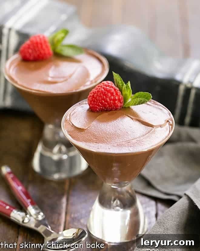 Two glasses of Chocolate Truffle Mousse topped with a raspberry and sprig of mint.