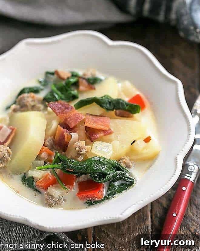 A steaming bowl of homemade Zuppa Toscana, overflowing with Italian sausage, crispy bacon, tender potatoes, and vibrant spinach.