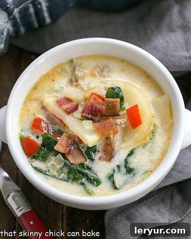 An overhead shot of Zuppa Toscana in a white bowl, showcasing the rich, creamy texture and vibrant ingredients.
