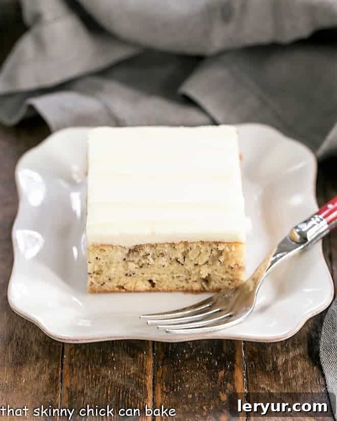 Sour Cream Banana Cake - a tender banana cake topped with a luscious layer of cream cheese frosting! Sour Cream Banana Cake on square ceramic plate.